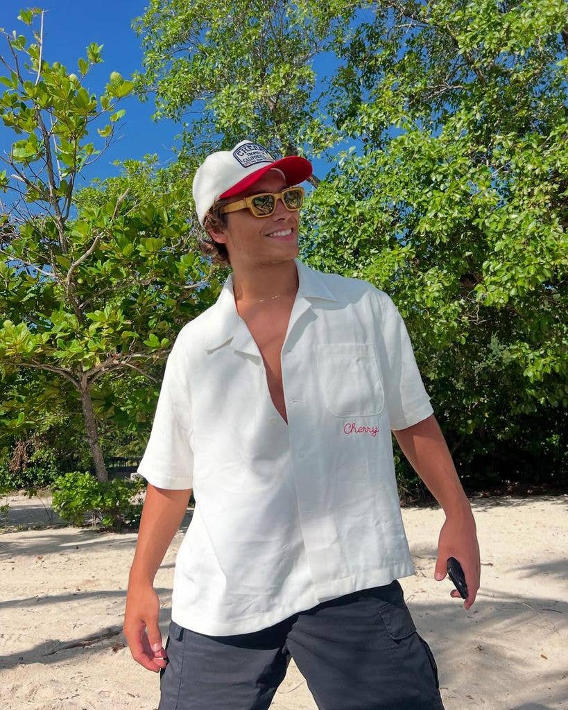 Joaquin posing in white shirt and baseball cap smiling