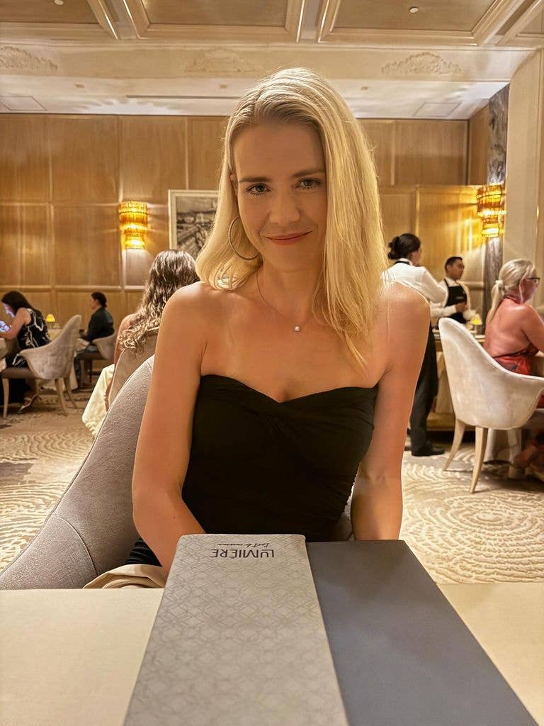 Elizabeth Smart sitting at a table looking sunkissed and smiling 