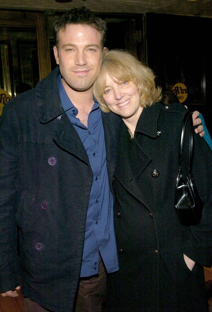 Ben Affleck smiling and posing with a woman in black coat.