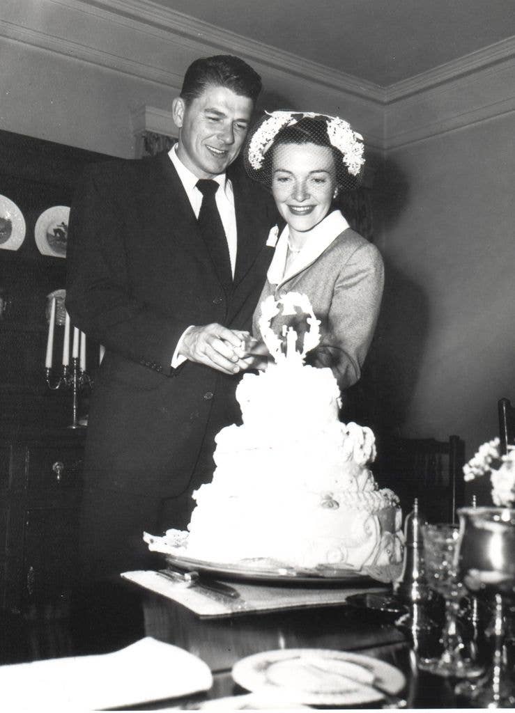 Married actors Ronald and Nancy Reagan cutting cake following their wedding ceremony.