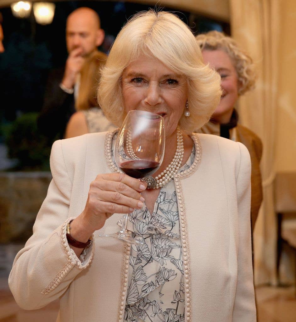 Queen Camilla holds a glass of red wine up to her mouth in 2017.