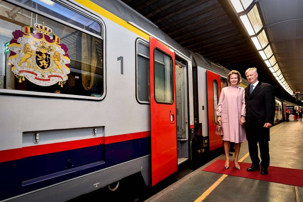 Philippe of Belgium and Queen Mathilde stand beside a train, smiling.