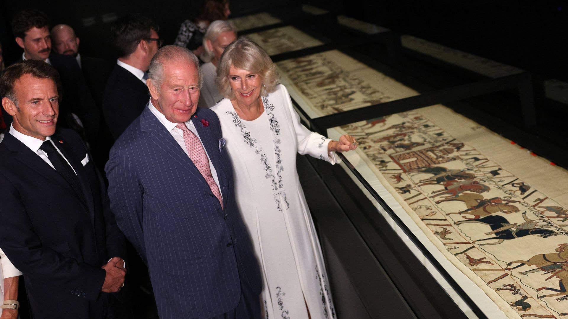 Emmanuel Macron, King Charles, and Queen Camilla view an exhibit.