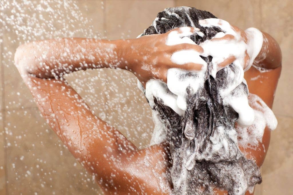 Woman washing her hair with shampoo, rear view